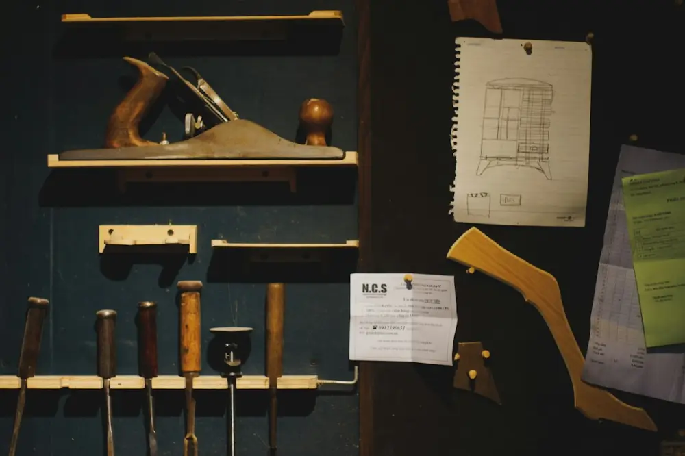 Woodworking tools and blueprints organized on a dark workshop wall, illustrating professional woodworking certification